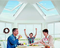 Familie beim Spielen am Esstisch unter 2 Dachfenstern
