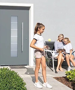 Spielende Kinder mit Mutter vor einer Haustür